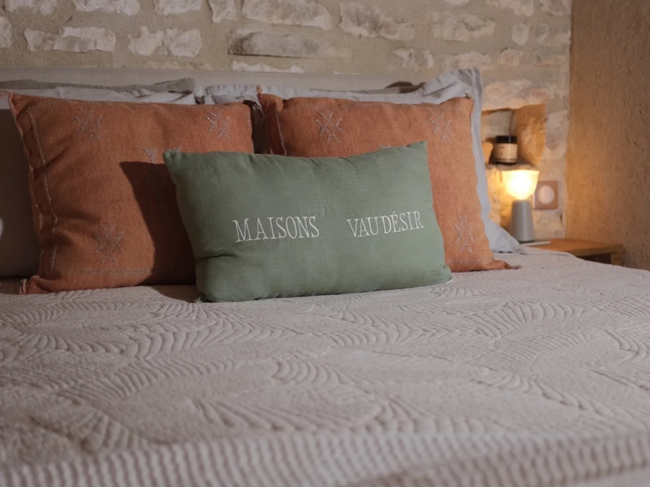 Kipli bed with terracotta cushions against a bare limestone wall