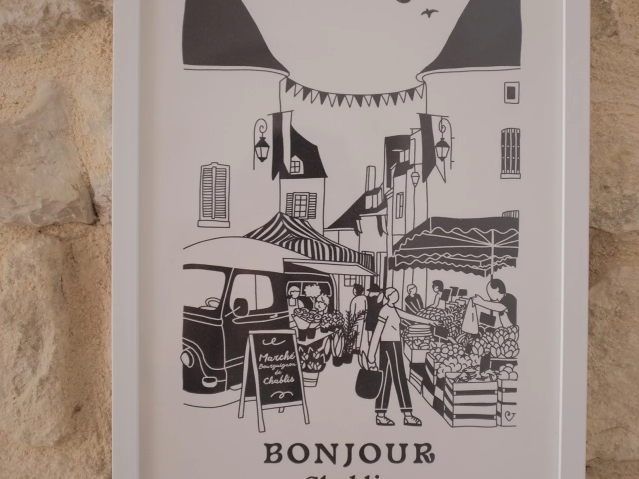 Framed Bonjour Chablis market print on a limestone wall