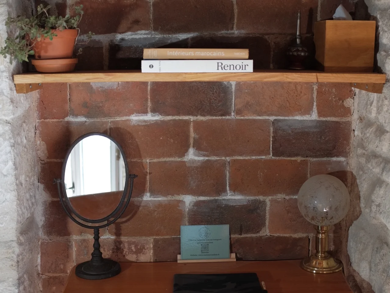 Small wooden desk set into a brick alcove with a tilting mirror