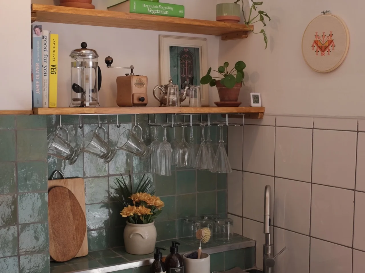 Kitchen with green zellige tile, black granite counter and hanging glassware