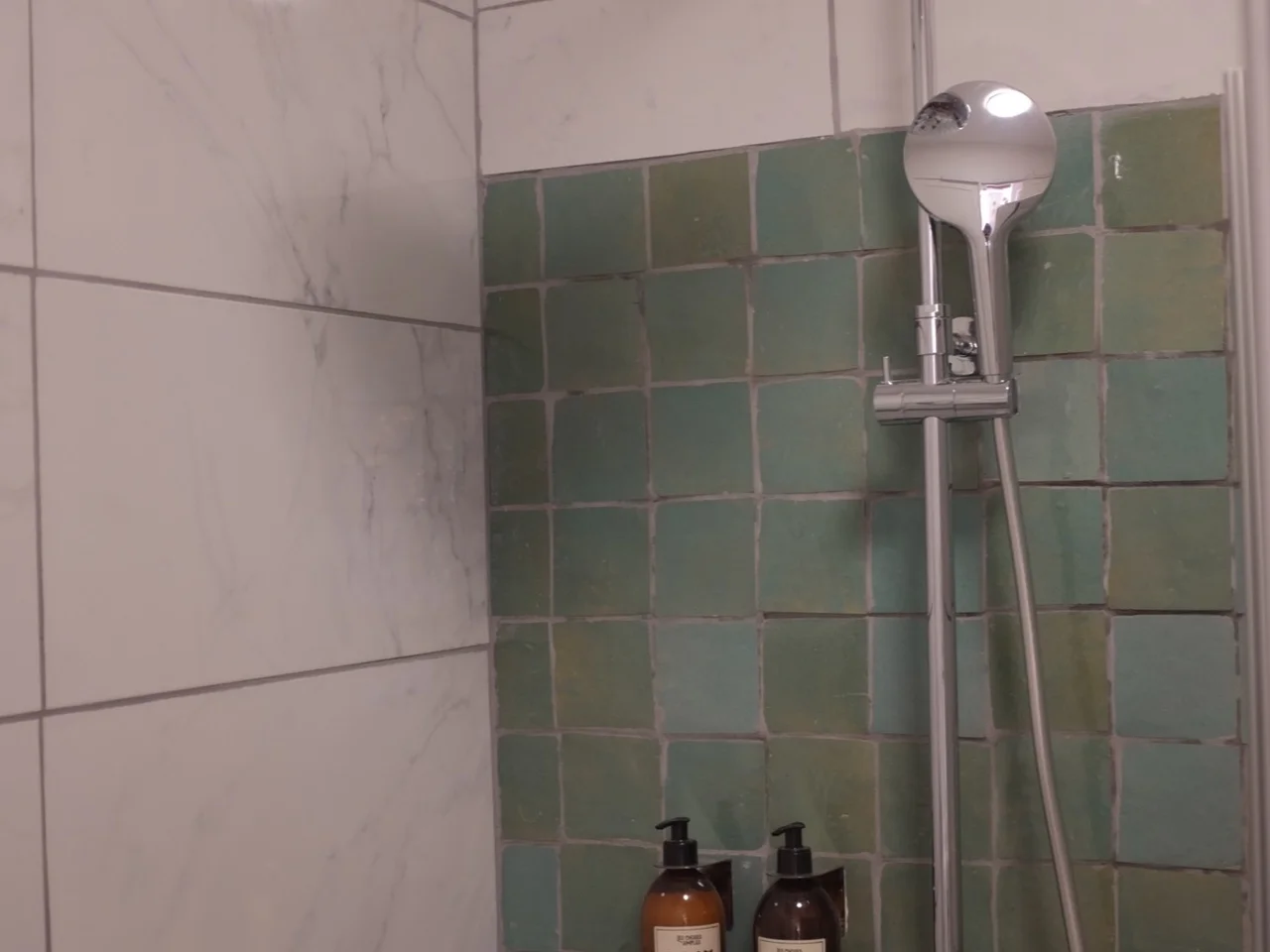 Walk-in rain shower with green zellige and marble tile