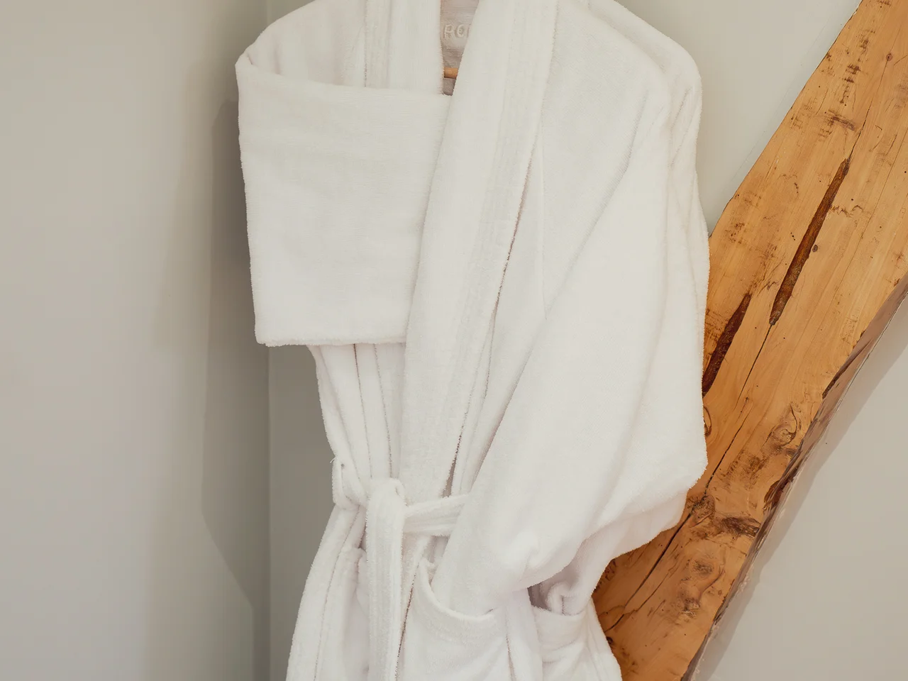 Plush white bathrobes on wooden beam